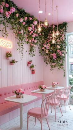 the interior of a restaurant with pink chairs and flowers hanging from the wall above them