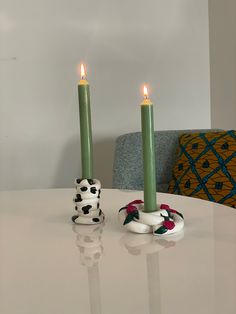 two candles sitting on top of a white table with dalmatian figurines