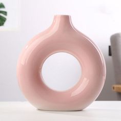 a pink vase sitting on top of a white table