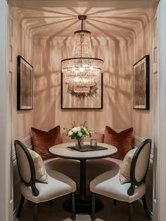 a dining room table with two chairs and a chandelier hanging from the ceiling