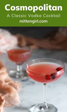 two cocktail glasses filled with red liquid and garnished with cherries