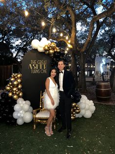 a man and woman posing for a photo in front of balloons