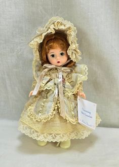 a doll is dressed in an old fashioned dress and bonnet with a name tag on it