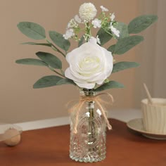 a white rose in a glass vase on a table