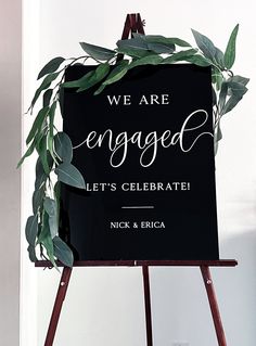 a sign that says we are engaged and let's celebrate with greenery on it