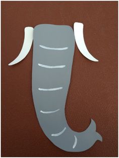 an elephant cut out from paper sitting on top of a brown surface with white lines