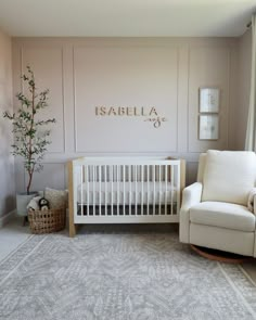 a baby's room with a white crib, chair and potted tree