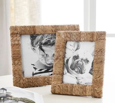 two frames are sitting on a table next to an open book, and one is holding a pug