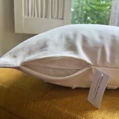 a white pillow sitting on top of a bed next to a window with a price tag