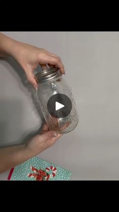 someone is holding a mason jar in their hand and opening it with the lid open