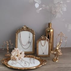 an assortment of jewelry is displayed on a wooden table next to a vase with flowers