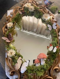 a mirror that is sitting on top of a table with flowers and butterflies around it