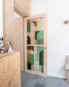 an open wooden door with stained glass panels on the front and back doors, in a white room