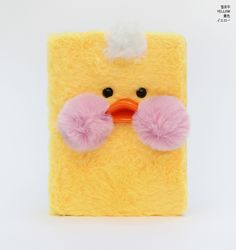 a yellow and pink stuffed animal with pom - poms on it's eyes