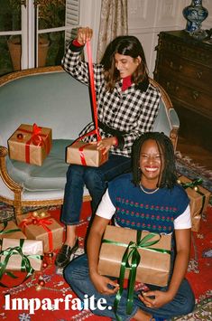 two women sitting on the floor with presents wrapped in brown paper and red ribbon around their necks