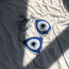 two blue and white crocheted eyeballs are laying on a bed sheet