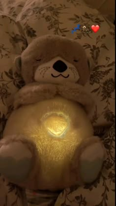 a brown teddy bear sitting on top of a bed next to a light up lamp