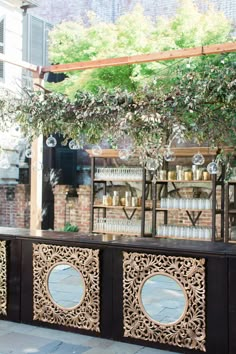 an outdoor bar with wine glasses hanging from it's ceiling and greenery on top