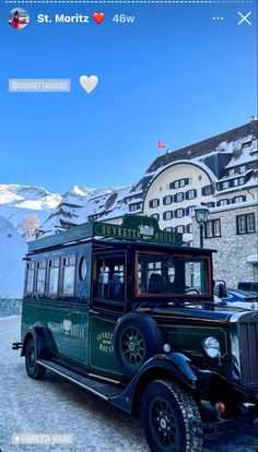 an old green bus parked in front of a building with snow on the mountains behind it