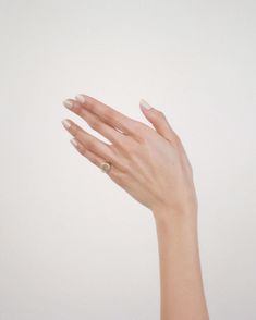 a woman's hand with white manicures and a ring on her finger