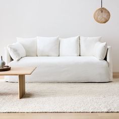 a white couch sitting on top of a wooden table in front of a white wall