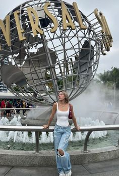 a woman standing in front of a fountain with the word universal on it's side