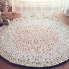 a round rug on the floor in front of a window with teddy bears and stuffed animals