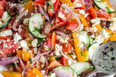 a salad with tomatoes, cucumbers, onions and feta cheese in a white bowl