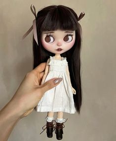 a doll is being held up by a person's hand with long black hair