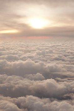 the view from an airplane looking down at clouds and sun in the sky above them