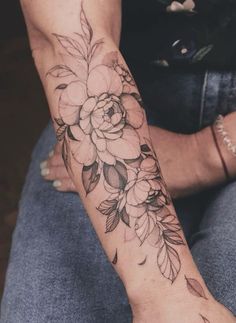 a woman's arm with flowers and leaves tattooed on the side of her arm