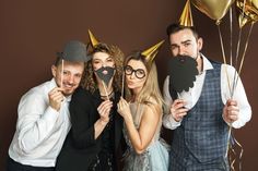 a group of people standing next to each other holding up paper masks with mustaches on them