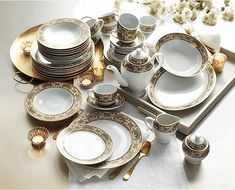 a table topped with lots of white and gold plates