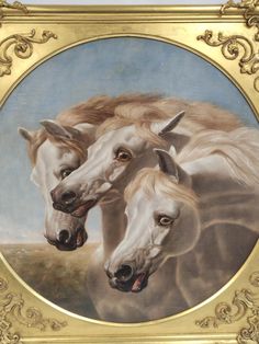 two white horses standing next to each other in a gold framed painting on the wall