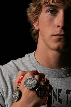 a young man with curly hair wearing two rings