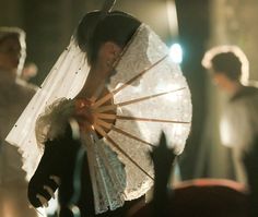 black and white photograph of a woman holding an umbrella in front of other people at a wedding