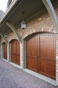 two brown garage doors in front of a brick building with arched doorways on either side