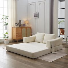 a living room with white furniture and wood floors