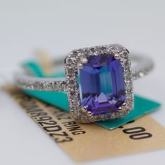 an amethorate and diamond ring sitting on top of a price tag