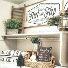 a shelf filled with towels and other items on top of a white counter next to a potted plant