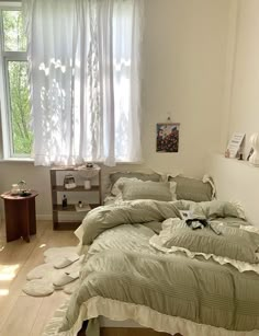 a bed room with two beds covered in green sheets and pillows next to a window