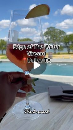 someone holding up a wine glass with the words edge of the water vinyard, dallas tx