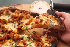 a person is holding a slice of pizza on a cutting board with a spatula