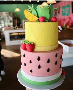 a three tiered cake decorated with fruit and pineapples on the top layer