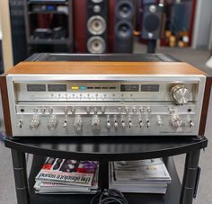 an old fashioned radio sitting on top of a black stand in front of some stereo equipment