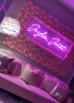 a living room filled with furniture and a neon sign on the wall above it's headboard