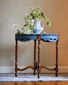 a blue table with flowers on it and a white vase sitting on top of it