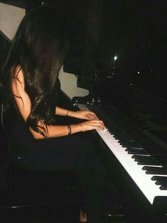 a woman sitting at a piano playing it