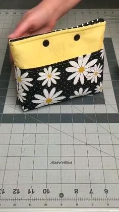 someone is cutting out the pattern for a small bag with flowers on it, and measuring tape