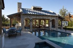 a backyard with a pool and basketball hoop in the center, surrounded by stone buildings